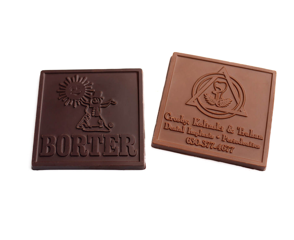 Two square brown chocolate bars on a plain white background, one dark chocolate embossed with 'BORTER' and a sun motif, and one lighter milk-chocolate bar embossed with a logo and business text.