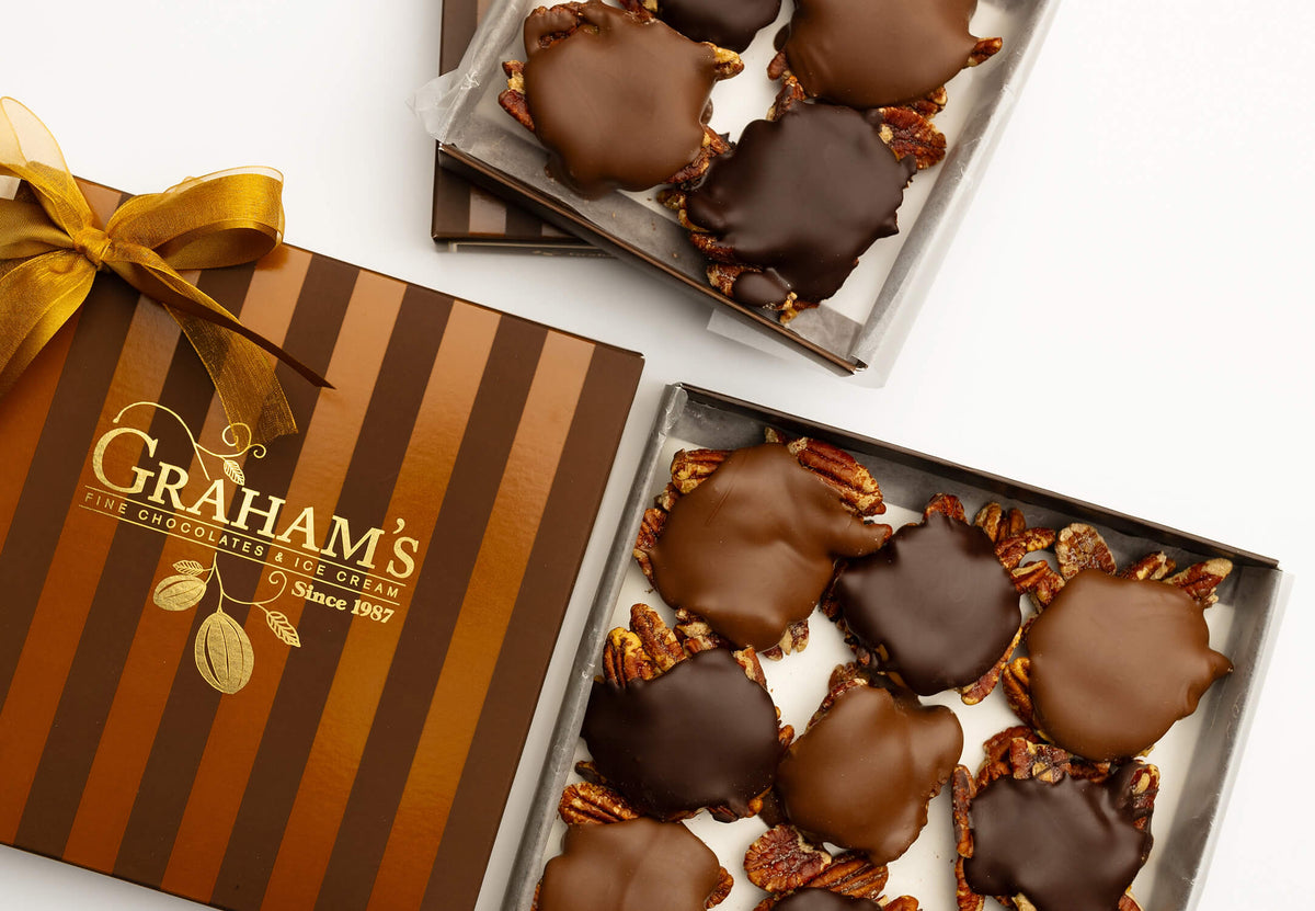 Graham's chocolate crumb cookies in two open boxes, with one closed box and a gold ribbon on the left, photographed on a white background.