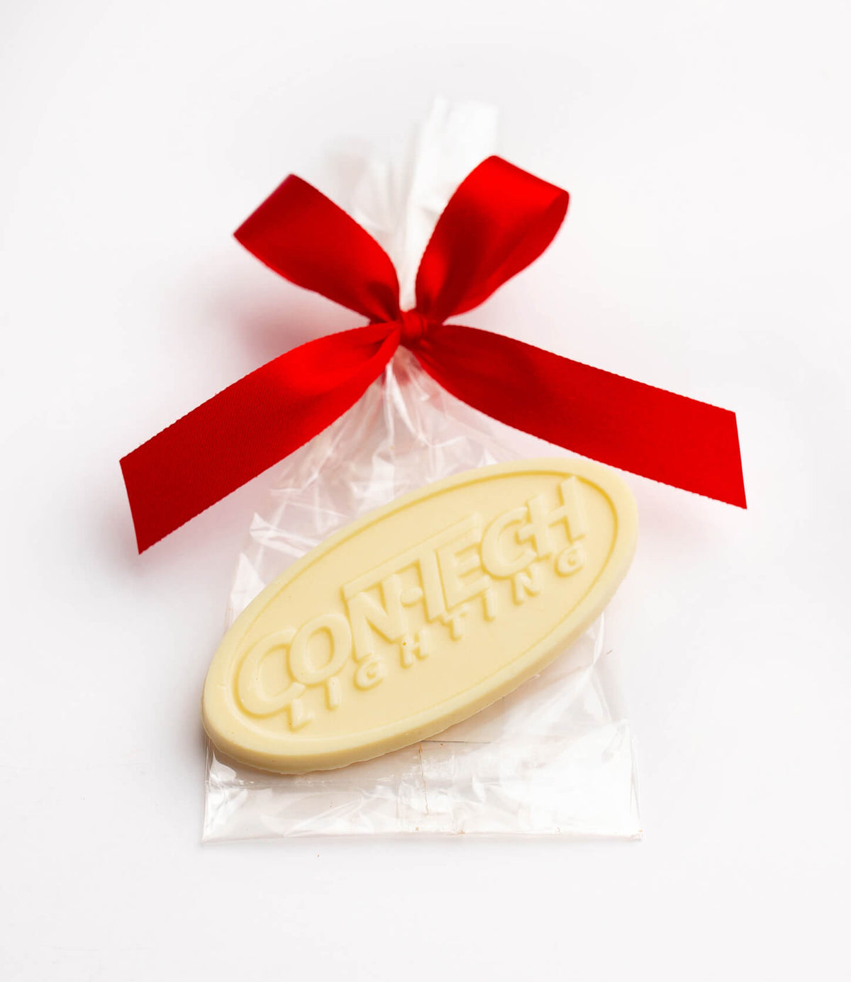 An oval cream-colored soap bar embossed with 'CONNECT STAYING' on a clear cellophane bag tied with a bright red ribbon, set against a plain white background.
